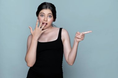 Young charming caucasian teenager girl with clean and fresh skin posing pointing fingers on empty background for beauty advertising. Cute smiling expression. Present beauty skincare cosmetic product.