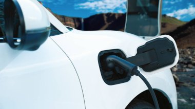 Elektro jeneratör sürücüsüyle enerji sürdürülebilir araba gücü, şarj istasyonunda şarj edilen batarya, ilerici seyahat konsepti için dağ zeminine sahip. Temiz ortamın sembolü olarak doğadaki EV otomobil.