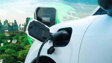 Gelişmiş yeşil şehir ESG sembolü elektrikli araçla arka plan, EV araba şarj noktasındaki enerji yenilenebilir enerji taşımacılığıyla çevre bilincini artırmak için şarj ediliyor.