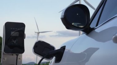 Çevreyi korumak için rüzgar türbininden yeşil ve yenilenebilir enerjiyle çalışan şarj istasyonunda şarj edilen gelişmiş gelecek enerji altyapısı konsepti.