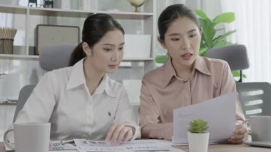 Ofis çalışma alanında birlikte çalışan iki genç hevesli iş kadını. Genç meslektaşlar tartışırken ve dizüstü bilgisayar kullanırken. Modern ofis çalışanları masada birlikte oturuyorlar..