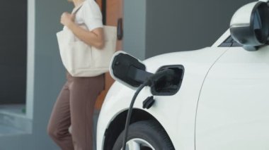 Bir kadın evinde elektrikli araç şarj aletinin fişini çekiyor. İlerici bir yaşam tarzında elektrikli araçların kullanımı, temiz ve sağlıklı bir çevreye katkıda bulunur..