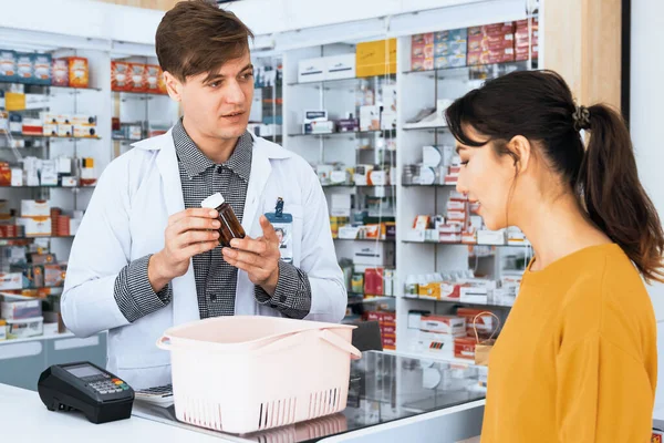 Professional pharmacist advise or explain property of qualified medical product to customer in pharmacy, druggist answer to client healthcare inquiry, medical service and consultation concept.