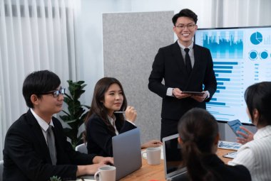 Confidence and asian businessman give presentation on financial analyzed by business intelligence in dashboard report to other people in board room meeting to promote harmony in workplace.