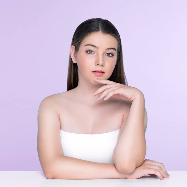 Портрет юной брюнетки с длинными волосами и безупречной кожей с жестом руки для красоты и косметической концепции. очаровательная красивая молодая девушка позирует руки для кожи или косметической рекламы.