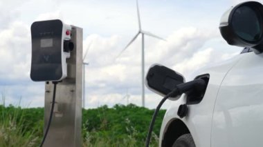 Çevreyi korumak için rüzgar türbininden yeşil ve yenilenebilir enerjiyle çalışan şarj istasyonunda şarj edilen gelişmiş gelecek enerji altyapısı konsepti.