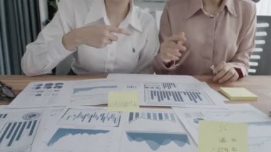 Ofis çalışma alanında birlikte çalışan iki genç hevesli iş kadını. Genç meslektaşlar tartışırken ve dizüstü bilgisayar kullanırken. Modern ofis çalışanları masada birlikte oturuyorlar..