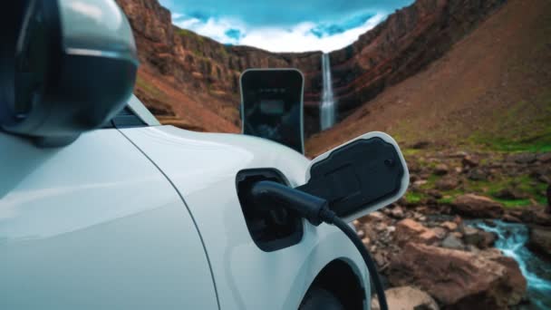 电动汽车在自然景观 瀑布和溪流背景下从充电站充电 可再生能源驱动的电动车能源可持续性的渐进概念 — 图库视频影像