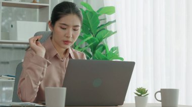 Ofiste çalışan ve dizüstü bilgisayar yazan hevesli bir iş kadını. Masasında oturmuş laptopla çalışan güzel bir ofis hanımı..