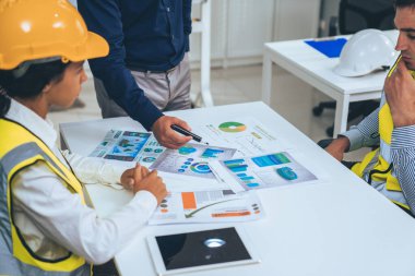 Engineers and competent employer discussing plans and blueprints together with tablet in the office. Concept of team contribution of ideas for engineering project.