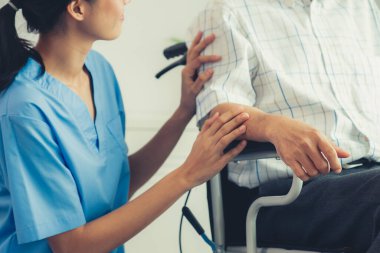 Happy positive asian nurse giving support and touching contented senior man with love. Nursing home for the elderly, elderly health and illness, senior patient carer.