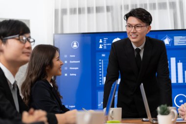 Confidence and asian businessman give presentation on financial analyzed by business intelligence in dashboard report to other people in board room meeting to promote harmony in workplace.