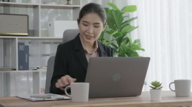 Ofiste çalışan ve dizüstü bilgisayar yazan hevesli bir iş kadını. Masasında oturmuş laptopla çalışan güzel bir ofis hanımı..