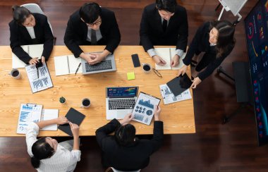 Top view manager or office worker give presentation in harmony conference room to business colleague, BI data dashboard on screen and pile of financial analyzed data reports on meeting table.