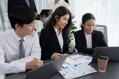 Harmony in office concept as business people analyzing dashboard paper together in workplace. Young colleagues give ideas at manager desk for discussion or strategy planning about project.