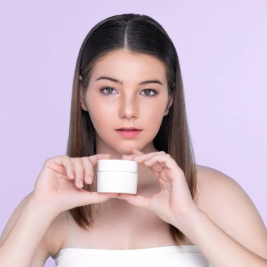 Young charming girl with natural beauty, perfect smooth skin hold lotion, cream, moisturizer jar. Beautiful girl show skincare product smiling on isolated background.