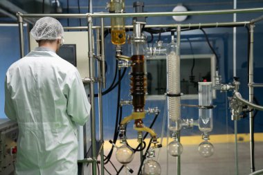 Bilim adamı ya da eczacı tıbbi ve sağlık hizmetleri için kenevir yağı çıkarıyor. Esrar ürünlerinden alınan sağlık hizmetleri eczanesi. Cam tüpler ve teçhizatlı kenevir yağı çıkarma makinesi.