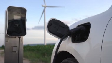 Çevreyi korumak için rüzgar türbininden yeşil ve yenilenebilir enerjiyle çalışan şarj istasyonunda şarj edilen gelişmiş gelecek enerji altyapısı konsepti.