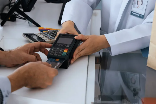 Payment by credit card with payment terminal in qualified drugstore or hospital. Modern payment of electric money. Closeup customer purchase medication in pharmacy with credit card on pos.