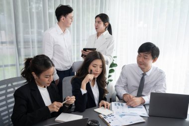 Harmony in office concept as business people analyzing dashboard paper together in workplace. Young colleagues give ideas at manager desk for discussion or strategy planning about project.