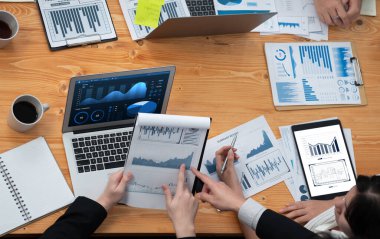 Top-view closeup business team of financial data analysis meeting with business intelligence, report paper and dashboard on laptop. Business group people working together in harmony office.