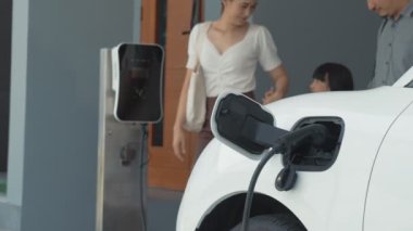 İlerici ebeveynler kızlarını okuldan alırken elektrikli araba ve yenilenebilir enerji kavramını kullandılar, evdeki EV otomobil için şarj istasyonu. Alternatif eko taşımacılığı.