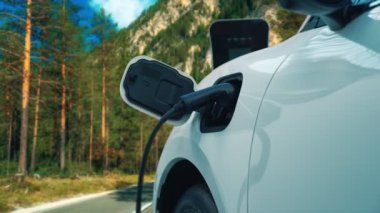 Elektrikli araç konsepti, yeşil çevre için yenilenebilir ve temiz enerjiyle çalışan EV otomobilinin varış noktasına ulaşmadan önce ormandaki şarj istasyonunun enerjisini şarj etmek için durur..