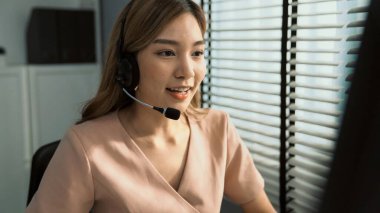 Competent female operator working on computer and while talking with clients. Concept relevant to both call centers and customer service offices.