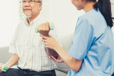 Contented senior patient doing physical therapy with the help of his caregiver. Senior physical therapy, physiotherapy treatment, nursing home for the elderly