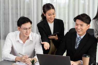 Harmony in office concept as business people analyzing dashboard paper together in workplace. Young colleagues give ideas at manager desk for discussion or strategy planning about project.