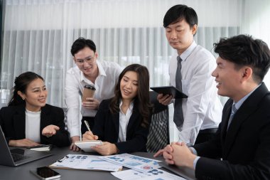 Harmony in office concept as business people analyzing dashboard paper together in workplace. Young colleagues give ideas at manager desk for discussion or strategy planning about project.