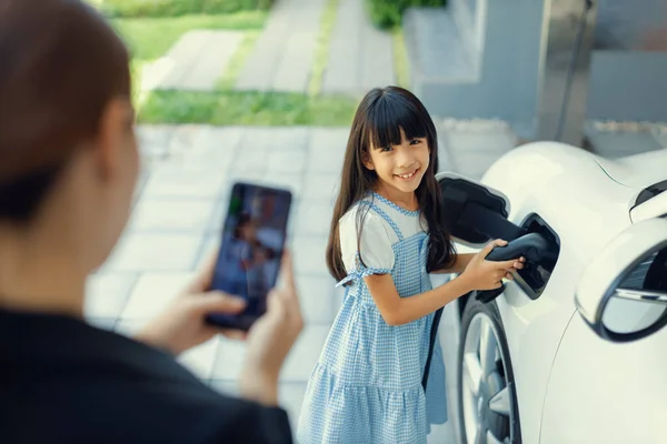 Progressive Mother Using Smartphone Take Focus Photo Daughter Recharge Car — Foto Stock