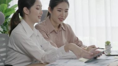 Ofis çalışma alanında birlikte çalışan iki genç hevesli iş kadını. Genç meslektaşlar tartışırken ve dizüstü bilgisayar kullanırken. Modern ofis çalışanları masada birlikte oturuyorlar..