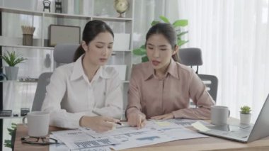 Ofis çalışma alanında birlikte çalışan iki genç hevesli iş kadını. Genç meslektaşlar tartışırken ve dizüstü bilgisayar kullanırken. Modern ofis çalışanları masada birlikte oturuyorlar..