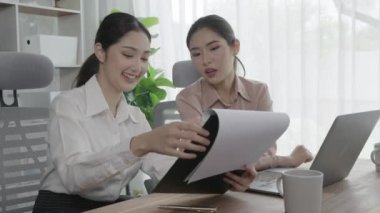 Ofis çalışma alanında birlikte çalışan iki genç hevesli iş kadını. Genç meslektaşlar tartışırken ve dizüstü bilgisayar kullanırken. Modern ofis çalışanları masada birlikte oturuyorlar..