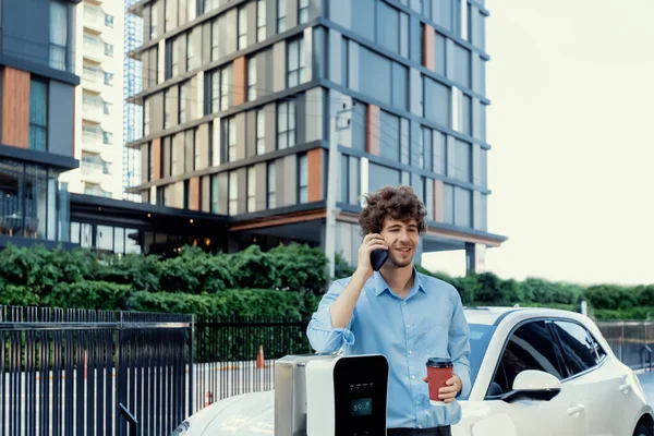 Progressive Businessman Talking Phone Coffee Leaning Electric Car Recharging Public — 图库照片