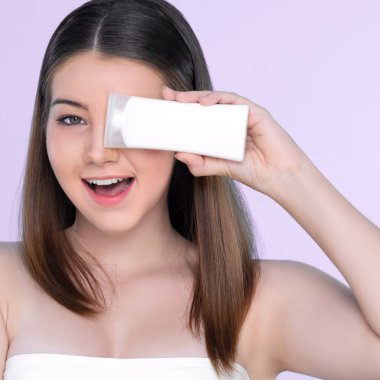Young charming girl with natural beauty, perfect smooth skin hold lotion, cream, moisturizer tube. Beautiful girl show skincare product smiling on isolated background.
