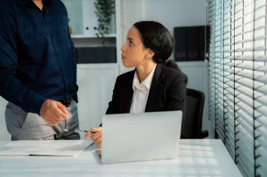 Competent female employee discussing with her colleague, employer using laptop at her office. Interpersonal relations among coworkers.