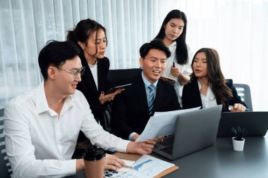 Harmony in office concept as business people analyzing dashboard paper together in workplace. Young colleagues give ideas at manager desk for discussion or strategy planning about project.