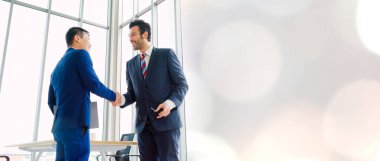 Business people handshake in corporate office in widen view showing professional agreement on a financial deal contract.