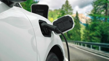 İlerici seyahat kavramı olan elektrikli araç, yeşil çevre için yenilenebilir ve temiz enerjiyle çalışan EV otomobilinin varış noktasına ulaşmadan önce uzak bölgedeki şarj istasyonundan enerjiyi şarj etmek için durur.