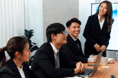 Confidence and young asian businesswoman give presentation on financial business strategy in dashboard report display on screen to colleagues in conference room meeting as harmony in workplace concept