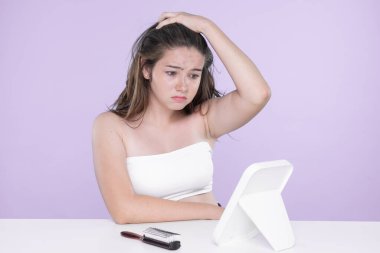 Young charming teenager girl worry about her face pimples on mirror for skincare and acne problem concept. Stress young girl squeezing pimples and pointing fingers on acne on her face.