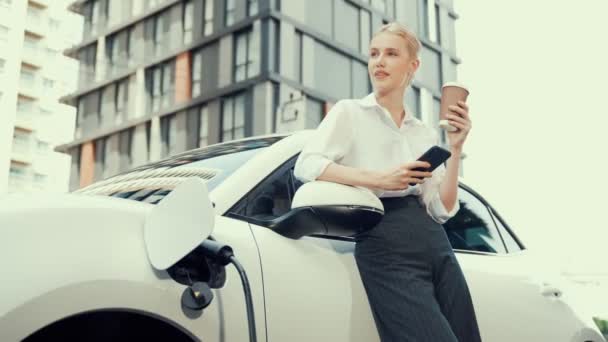 Postępowy Bizneswoman Opierając Się Elektrycznych Samochodów Stacji Ładowania Przed Jazdy — Wideo stockowe