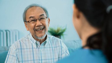 A young female doctor inquires about personal information of a contented senior at home. Medical care for the elderly, elderly illness, and nursing homes, home care.