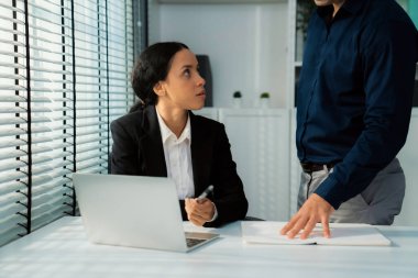 Competent female employee discussing with her colleague, employer using laptop at her office. Interpersonal relations among coworkers.