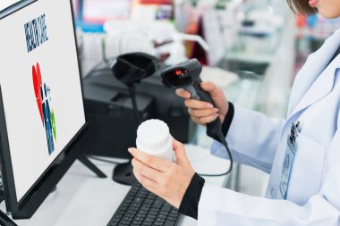 Eczanenin barkodunu tarayan genç eczacı, eczanenin eczane malzemesi, ilaç kutusu ya da şişesi için gerekli niteliklere sahip..