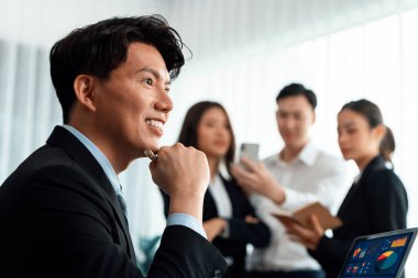 Portrait of focus young successful confident male manager, executive wearing business wear in harmony office arm crossed with blurred meeting background of colleagues, office worker.