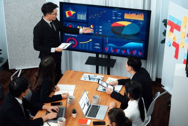 Confidence and asian businessman give presentation on financial analyzed by business intelligence in dashboard report to other people in board room meeting to promote harmony in workplace.