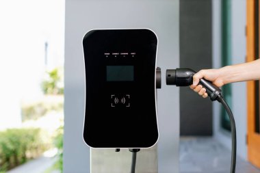 Yakından EV şarj prizi takın, EV araba için yeşil enerjili şarj noktası kavramı aşamalı ev şarj istasyonu garajına bağlı. Çevre dostu şarj edilebilir araba..